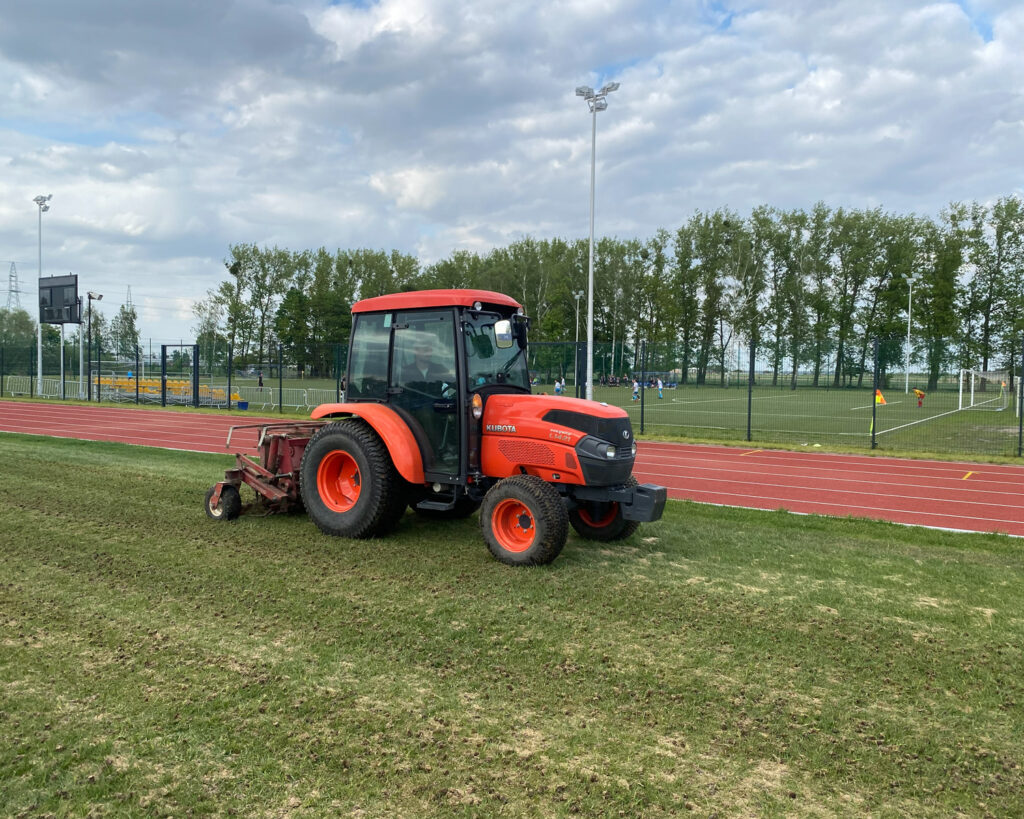 Aeracja rurkowa boiska sportowego przy użyciu traktora Kubota.