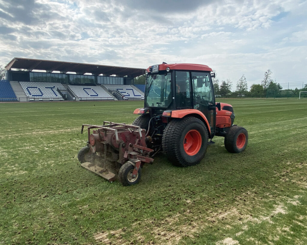 Aeracja rurkowa boiska sportowego przy użyciu traktora Kubota.